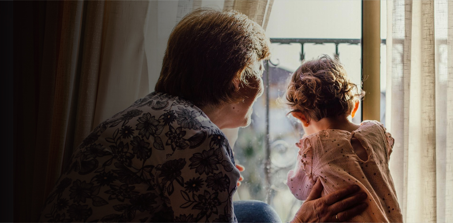 a senior gazes outside of a window with a toddler